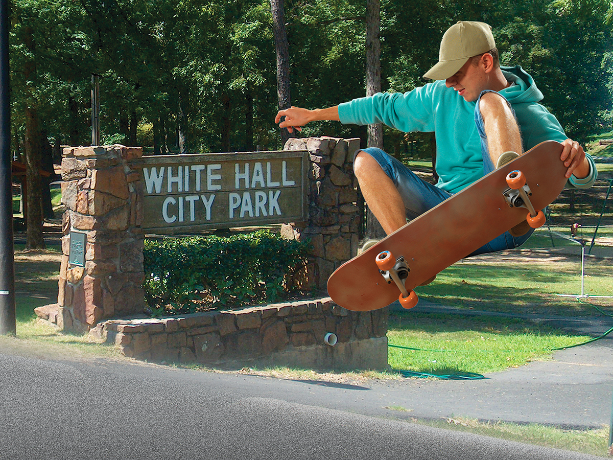 Skateboarder flies in the air near White Hall City Park entrance sign
